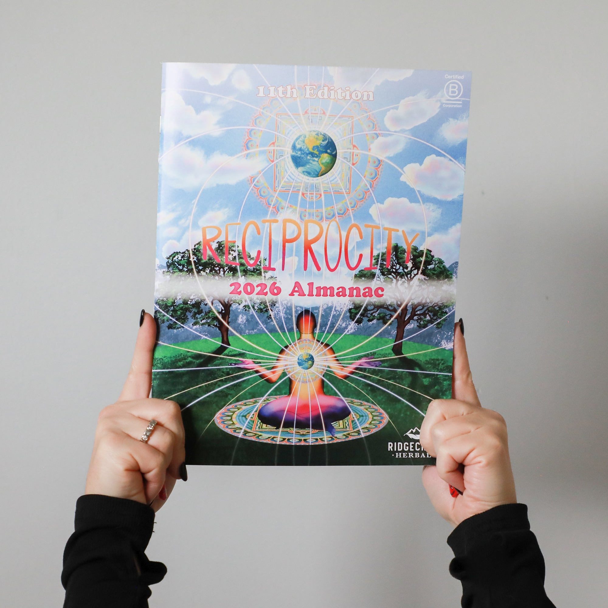 Two hands holding up the 2026 RidgeCrest Herbals Almanac