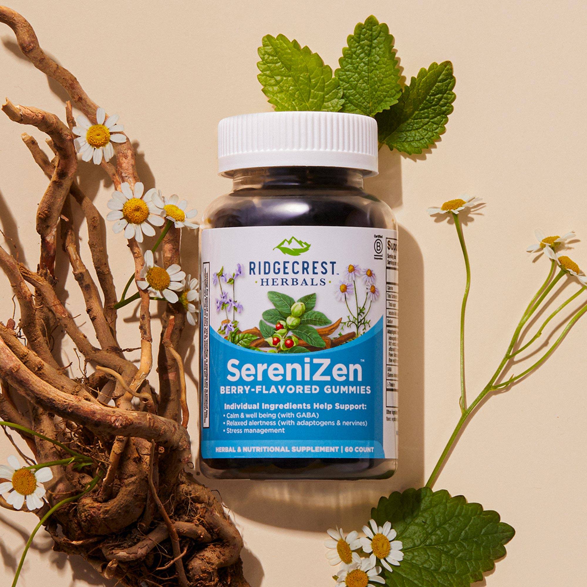 A bottle of SereniZen Gummies alongside chamomile flowers, roots, and green leaves on a beige background
