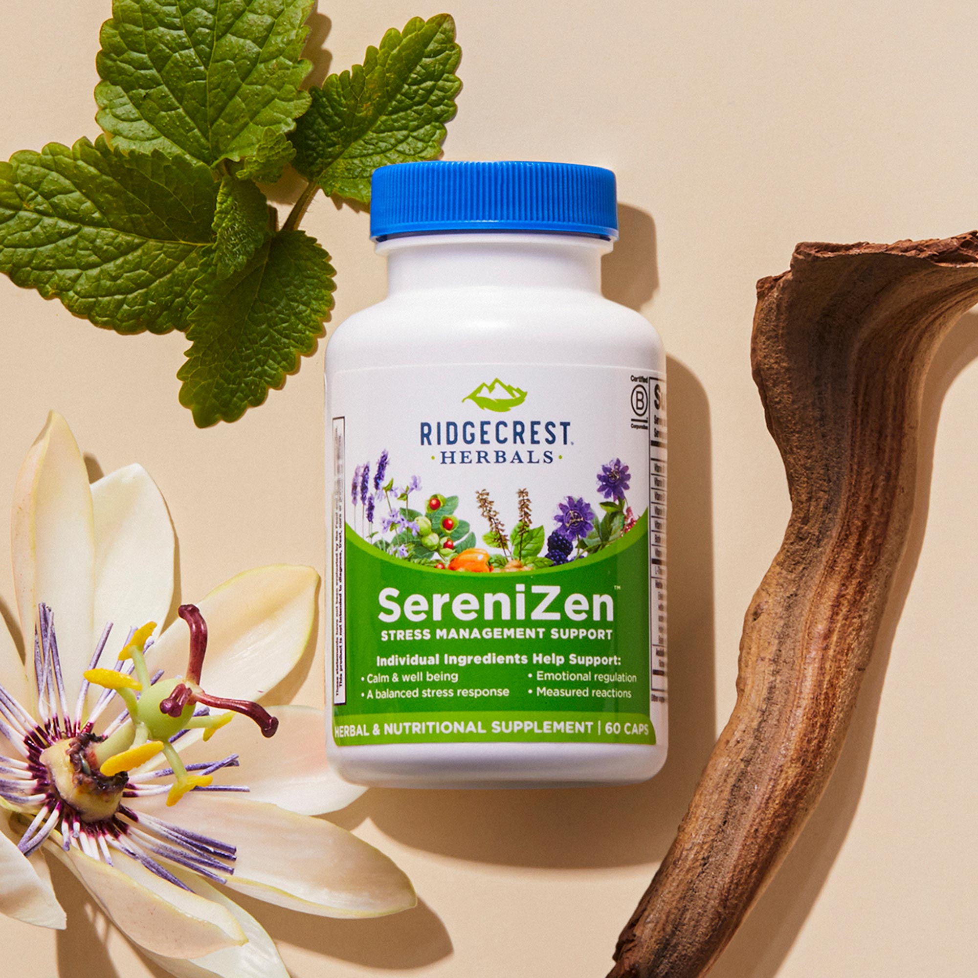 A bottle of SereniZen is surrounded by a passionflower, green leaves, and a piece of wood on a beige background