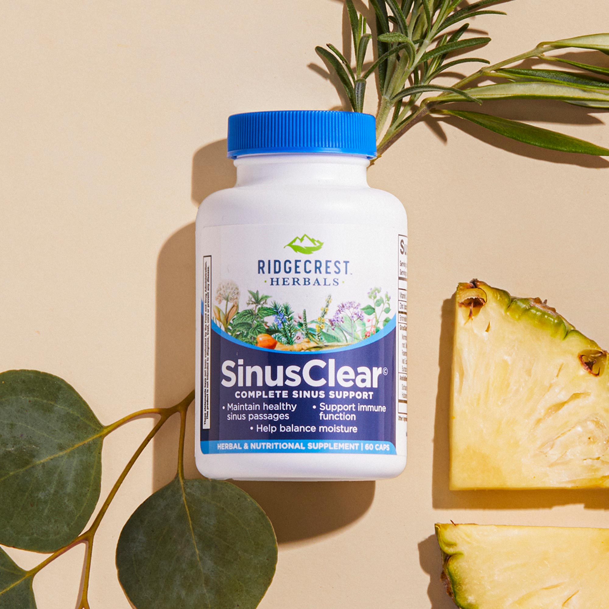 SinusClear bottle on a beige background, surrounded by rosemary, eucalyptus leaves, and pineapple slices.