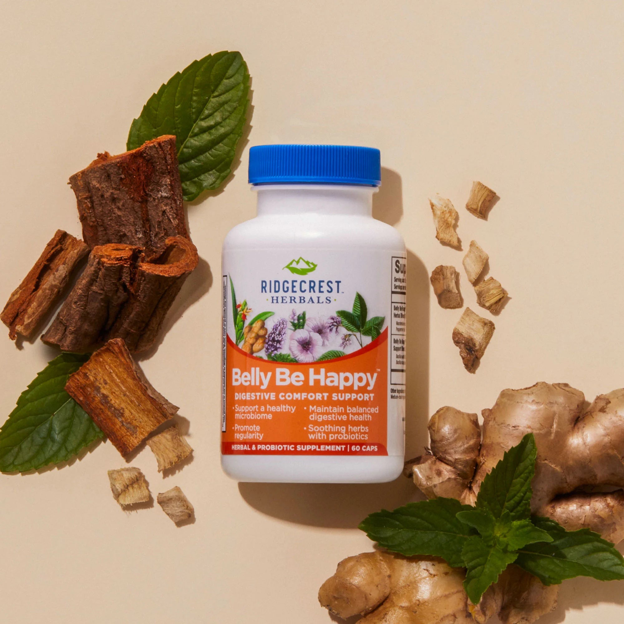 Belly Be Happy supplement is displayed with ginger root, cinnamon bark, and mint leaves, set against a beige background.