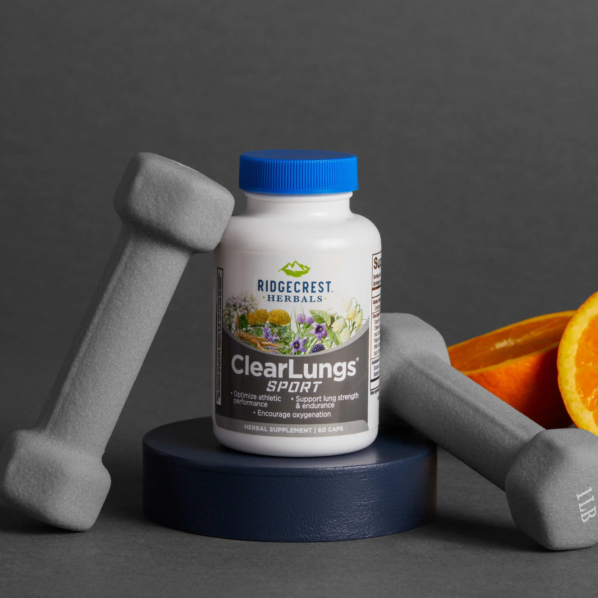ClearLungs Sport supplement is displayed alongside gray dumbbells and orange slices, set against a dark gray background.