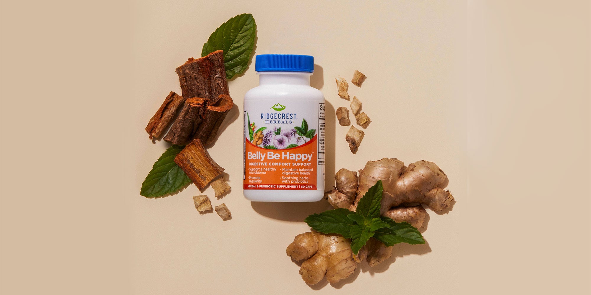 Belly Be Happy supplement is displayed with ginger root, cinnamon bark, and mint leaves, set against a beige background.