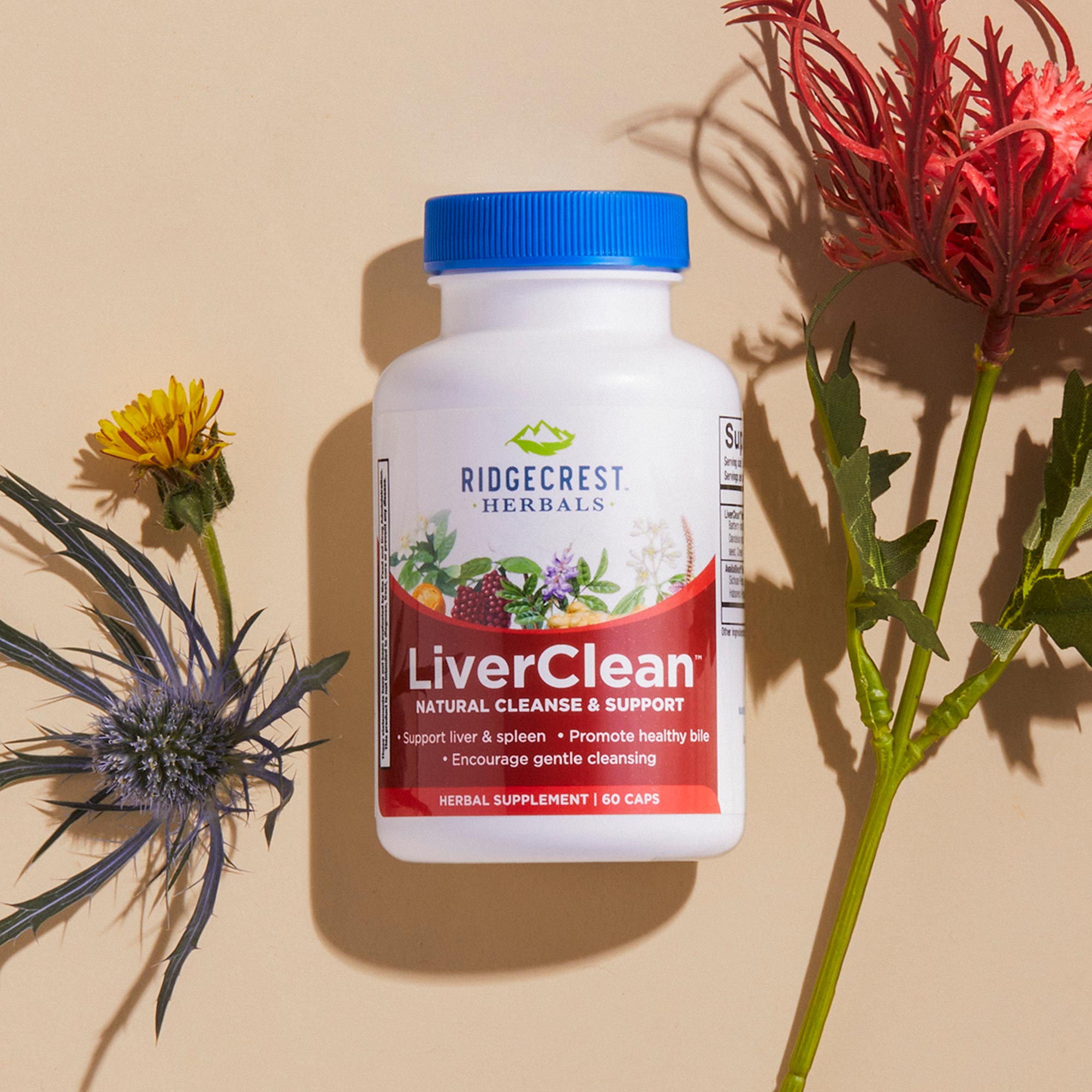 A bottle of LiverClean supplement, displayed with yellow dandelion, red hibiscus, and blue thistle flowers.