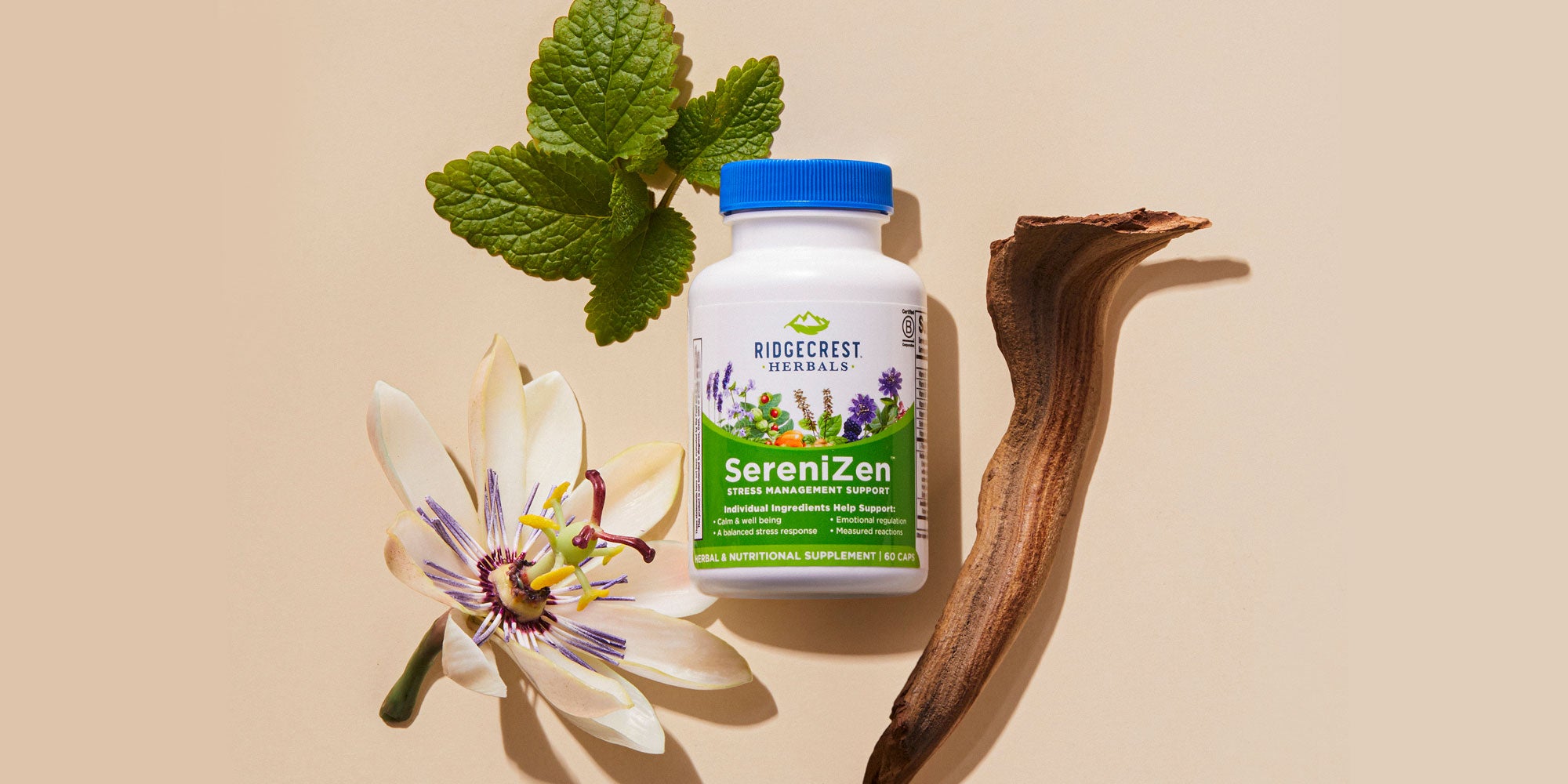 A bottle of SereniZen is surrounded by a passionflower, green leaves, and a piece of wood on a beige background