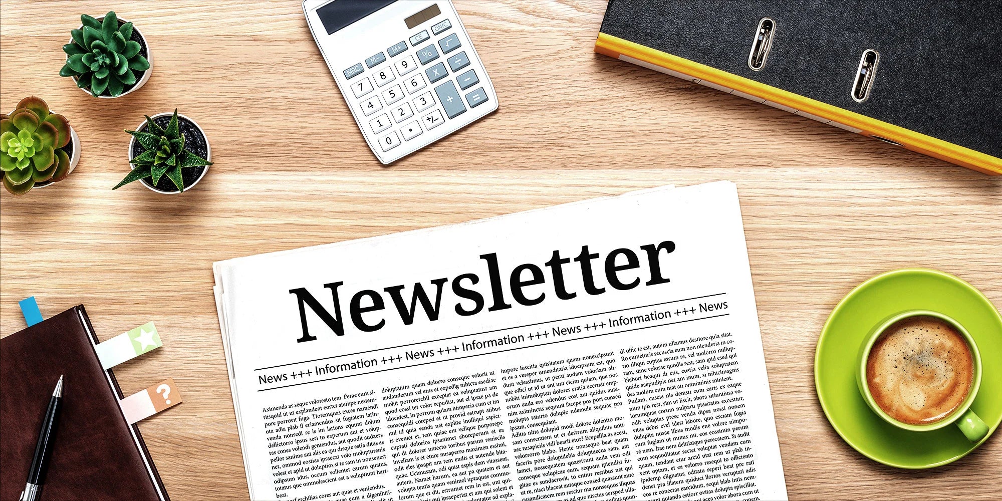 A newsletter spread on a wooden desk alongside a cup of coffee, a calculator, small plants, and office supplies.