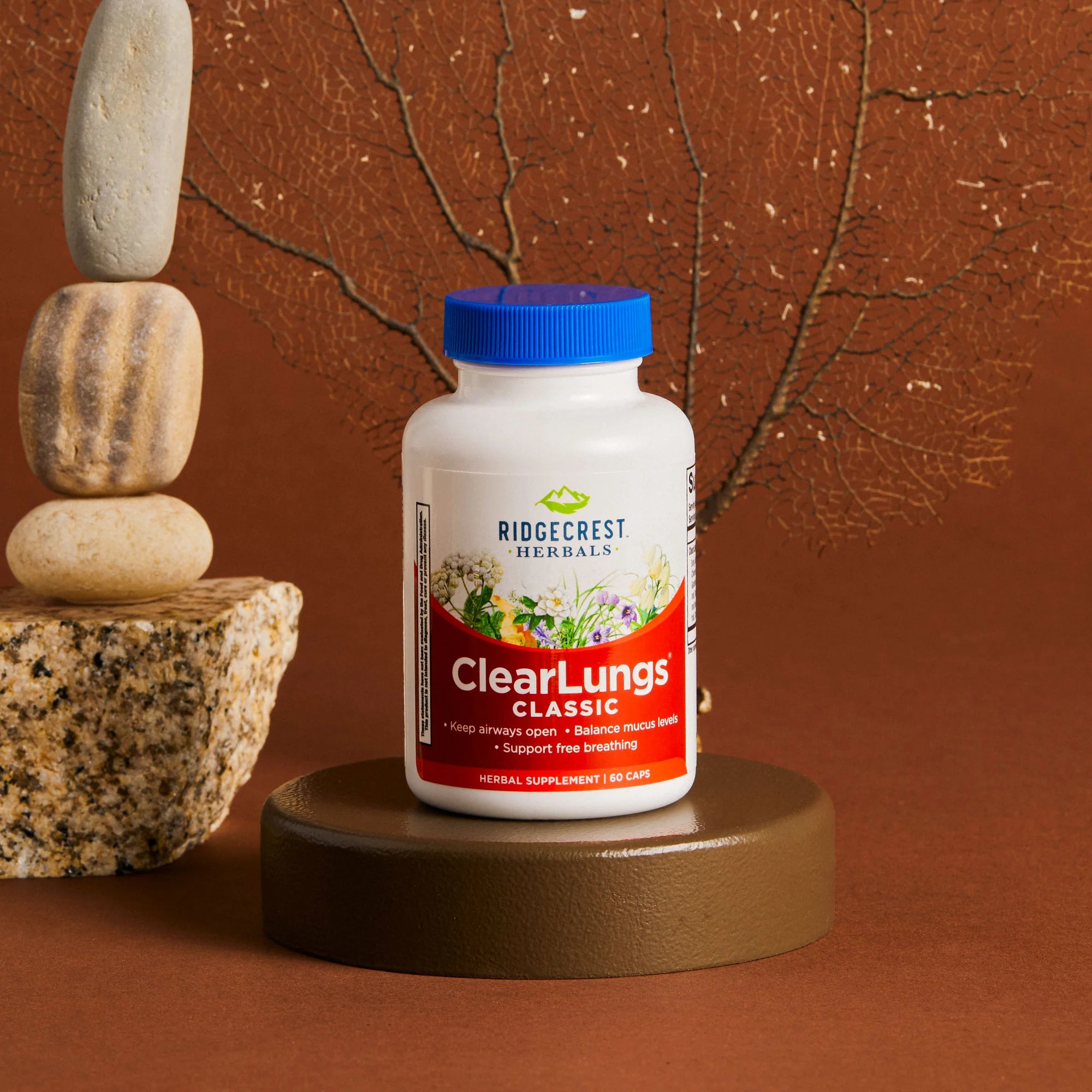 ClearLungs Classic supplement is displayed with stacked stones and a delicate dried branch, set against a brown background.