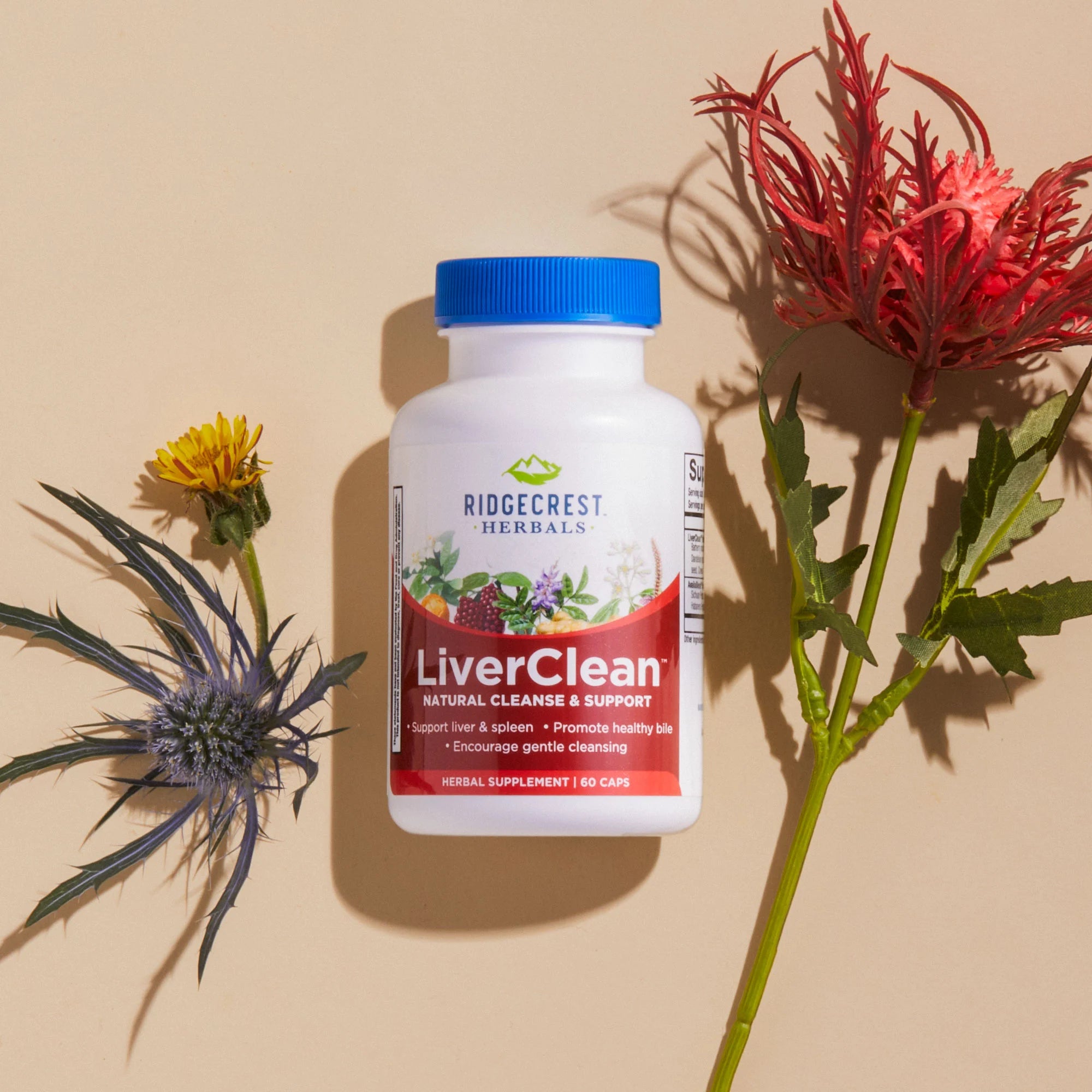 A bottle of RidgeCrest Herbals' LiverClean supplement, displayed with yellow dandelion, red hibiscus, and blue thistle flowers.