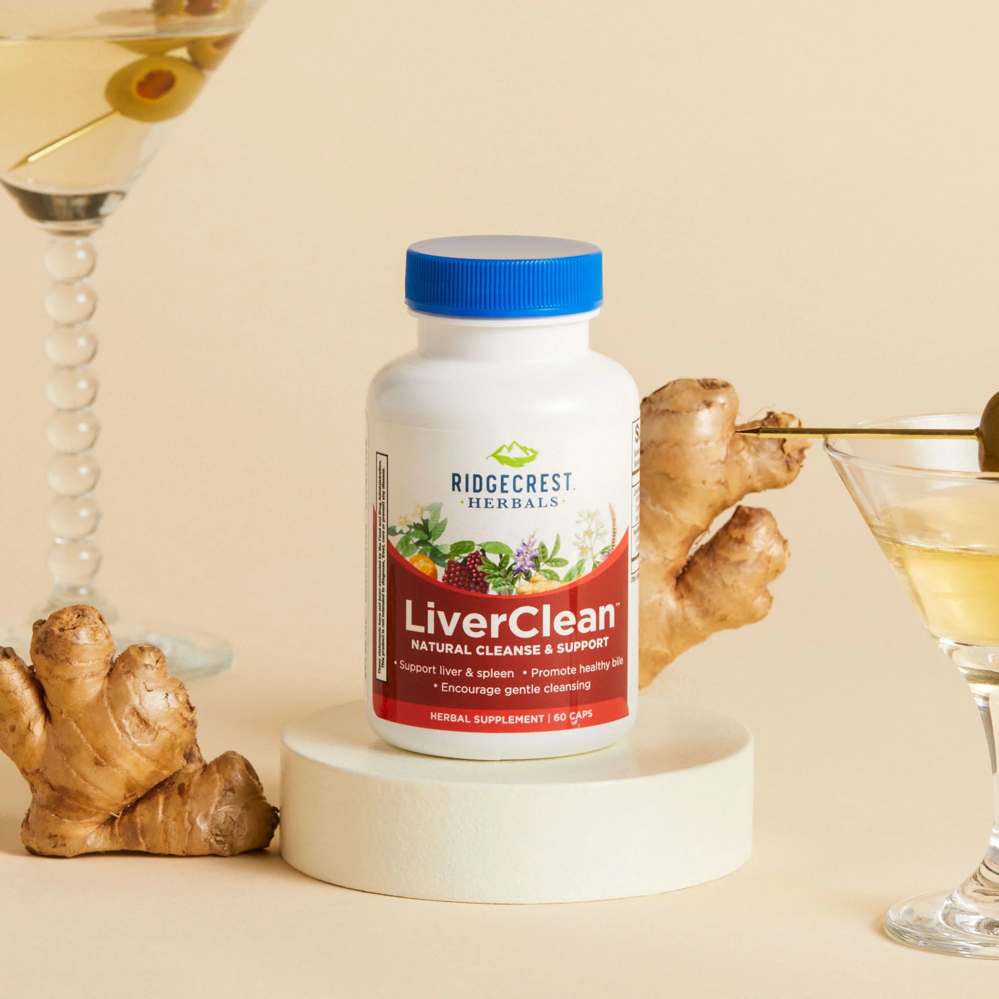 A bottle of RidgeCrest Herbals' LiverClean supplement is displayed with fresh ginger root and a martini glass with olives, set against a neutral background.