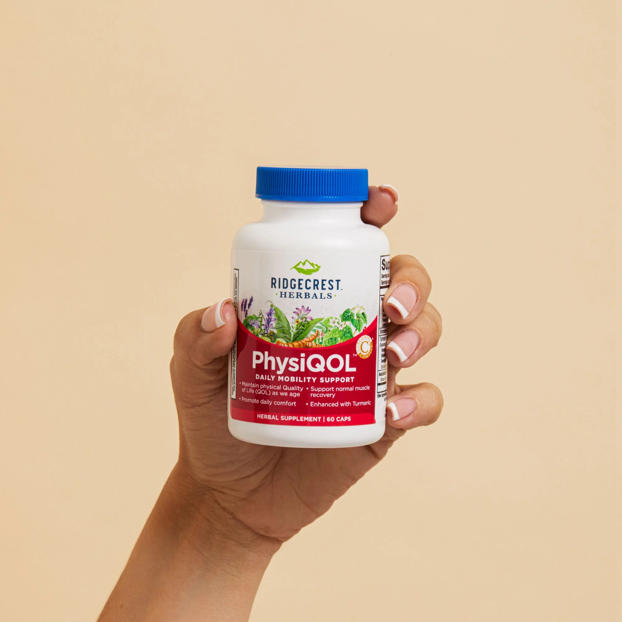 A manicured female hand holds a bottle of PhysiQOL against a beige background. 