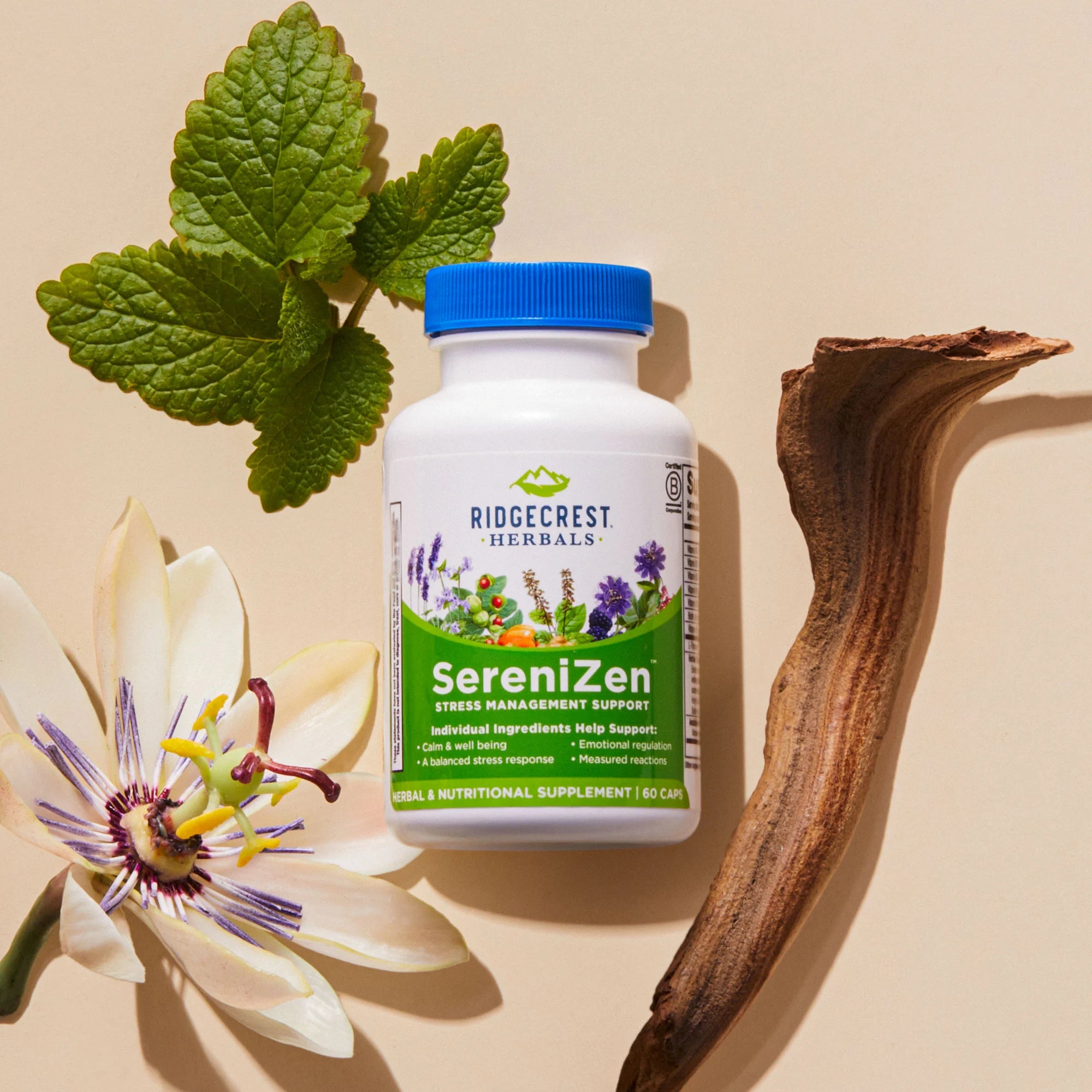 A bottle of SereniZen is surrounded by a passionflower, green leaves, and a piece of wood on a beige background