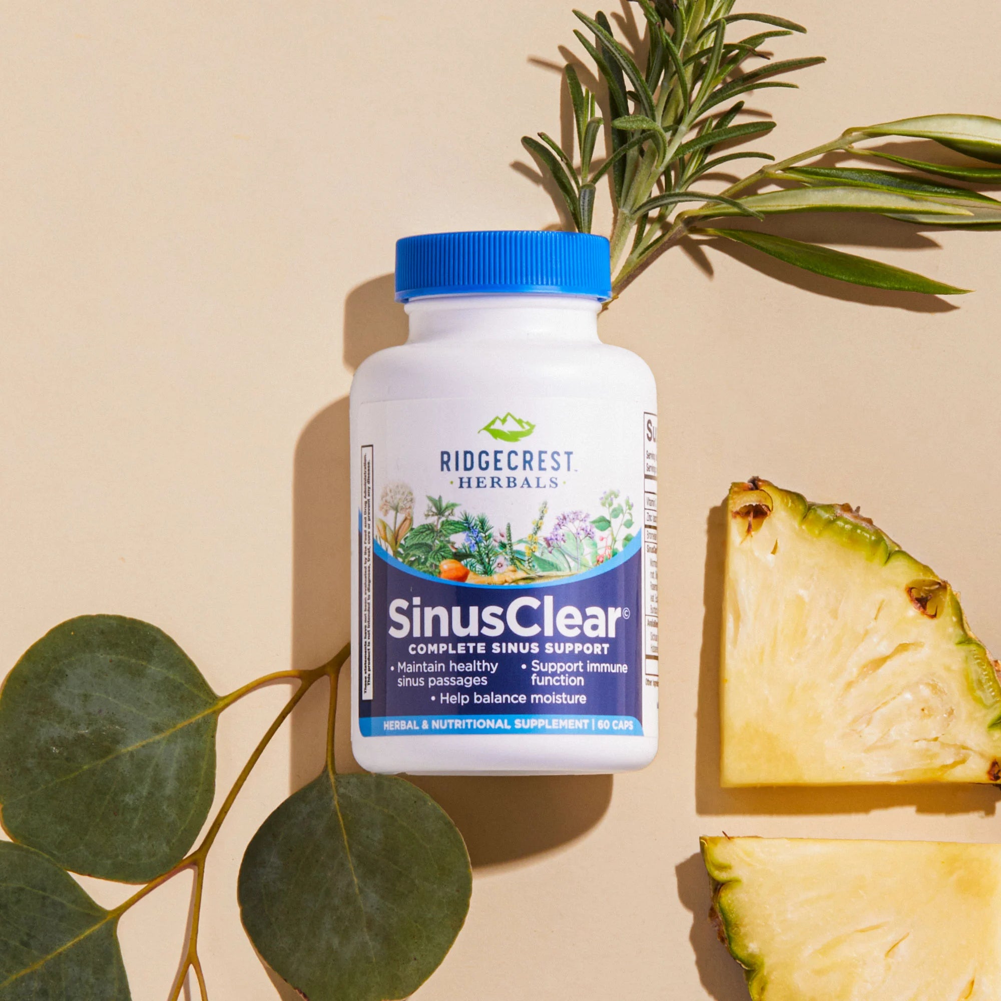 SinusClear bottle on a beige background, surrounded by rosemary, eucalyptus leaves, and pineapple slices.